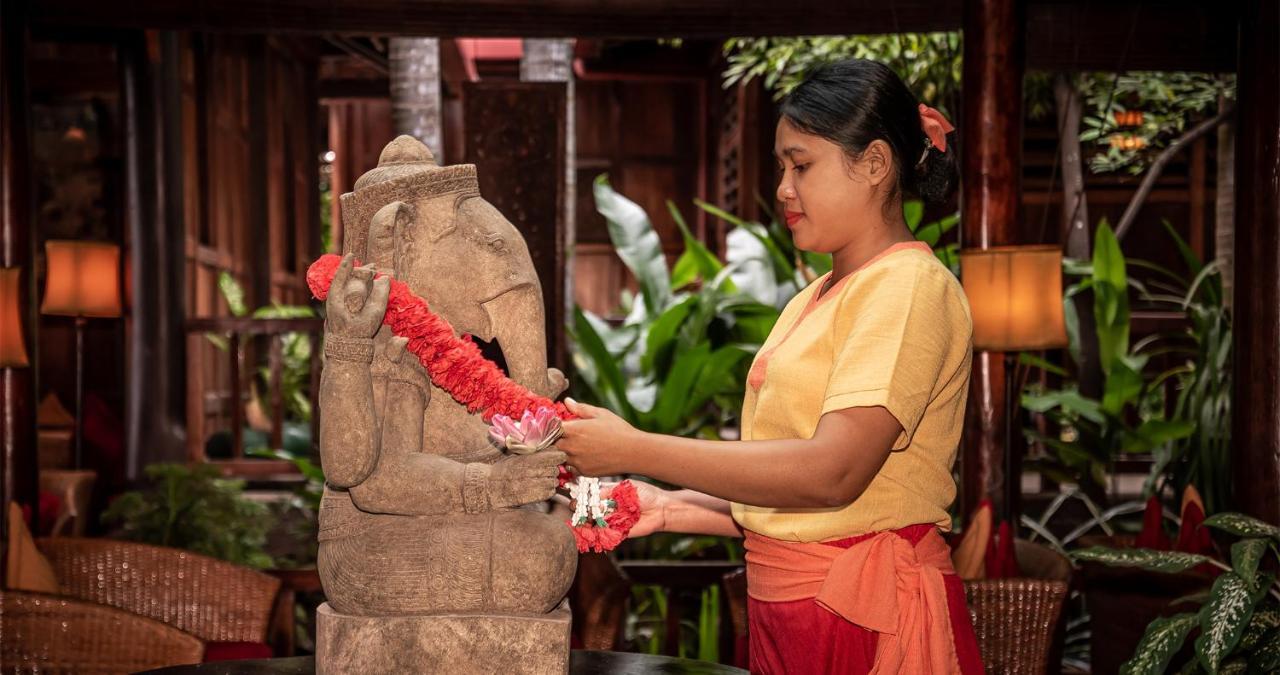 Angkor Village Hotel Siem Reap Eksteriør billede A woman in Thailand, wearing traditional Thai clothing, garlands a statue of the Hindu god Ganesha.